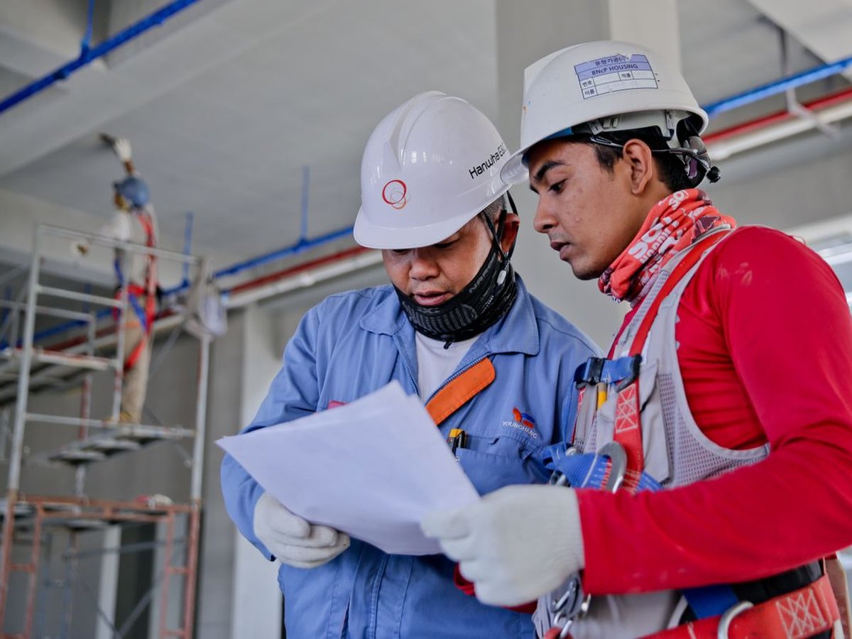 Builders in hard hats reviewing plans together on a construction site